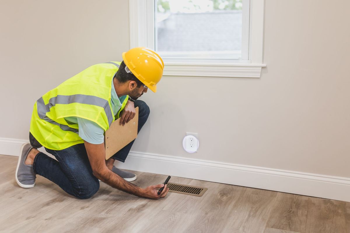 Home inspector checking a floor vent inside a house