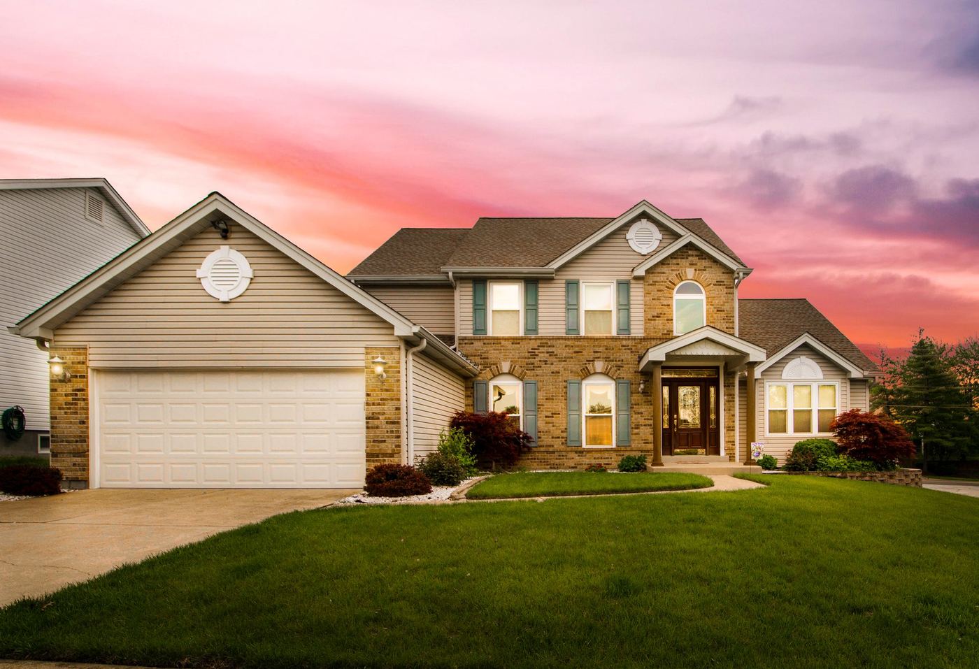 Two-story home with a stone front at sunset
