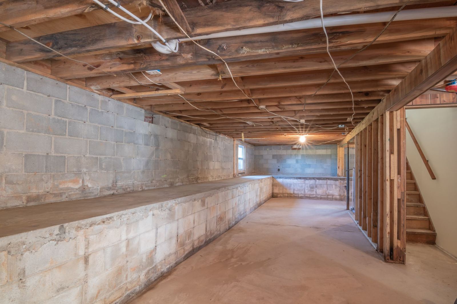 Unfinished space under a house with exposed joists and block walls