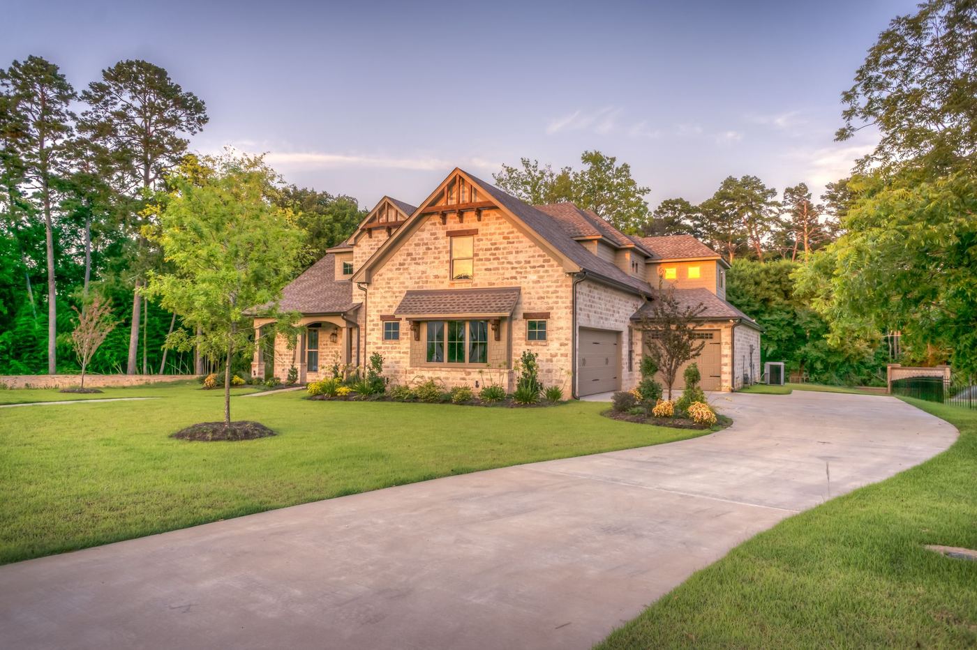 Stone home with a curved driveway and a green lawn