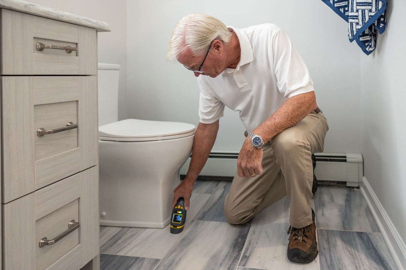 Technician using a handheld meter near the floor of a home